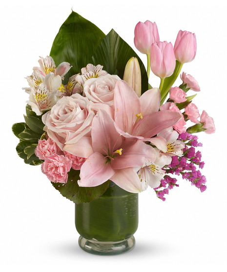 Pink roses, tulips, lilies and more in a hurricane vase