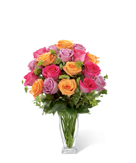 Hot pink, lavender and orange roses in a clear glass vase with greenery