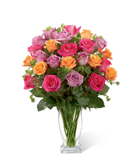 Hot pink, lavender and orange roses in a clear glass vase with greenery