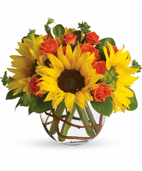 Bowl of yellow sunflowers and greenery in a clear glass vase