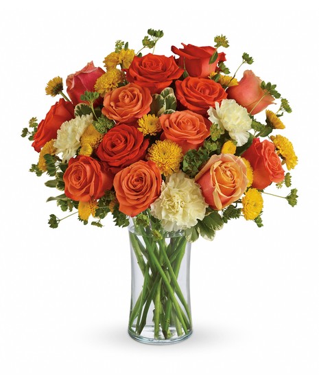 Bouquet of bright flowers and greenery in a clear glass vase